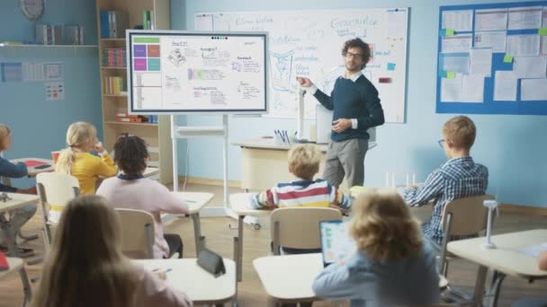 Grundskolans naturvetare använder interaktiv digital whiteboard för att visa klassrummet fullt av barn hur programvara programmering fungerar för robotteknik. Science Class, nyfikna barn lyssnar uppmärksamt — Stockvideo