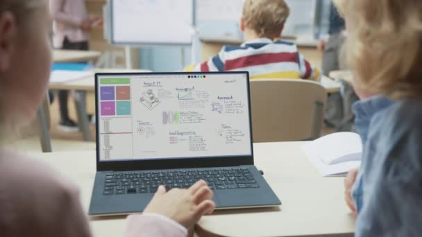 Початкова школа наукового класу: Над плечем двоє маленьких дітей використовують ноутбук з екраном, що показує програмне забезпечення для програмування нейронних мереж. Вчитель комп'ютерних наук пояснює урок класу — стокове відео