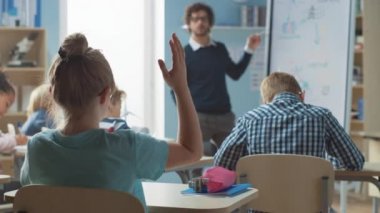 Parlak Öğrenci Kız Cevap Vermek İçin Elini Kaldırdı. Çok Irklı Öğrenen Çocuklar Grubu ile İlköğretim Okulu 'nda. Öğrenciye Odaklı Arka Görünüm Kamerası