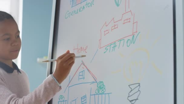 Elementary School Science Class: Portrait of Cute Girl Uses Interactive Digital Whiteboard to Show to a Full Classroom how Renewable Energy Works. Science Class, Curious Kids Listening. Slow Motion — Stock Video