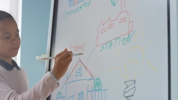 Elementary School Science Class: Portret van schattig meisje maakt gebruik van interactieve digitale whiteboard om te laten zien aan een volledige klas hoe hernieuwbare energie werkt. Wetenschapsles, nieuwsgierige kinderen die luisteren. Langzame beweging — Stockvideo