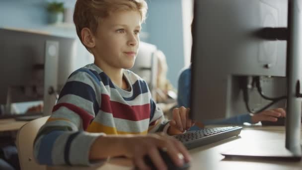 Základní škola učebna: Chytrý chlapec používá osobní počítač, naučit se bezpečně používat internet, programovací jazyk pro kódování softwaru. Školáci dostávají moderní vzdělání. Portrétní snímek — Stock video