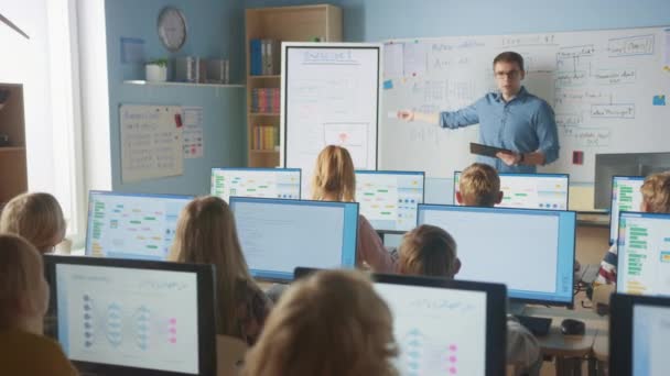 Basisschoolklas: Leraar maakt gebruik van interactieve digitale whiteboard, verklaart les aan diverse groep slimme kinderen. Kinderen krijgen modern onderwijs, computerwetenschappen leren, programmeren van software — Stockvideo