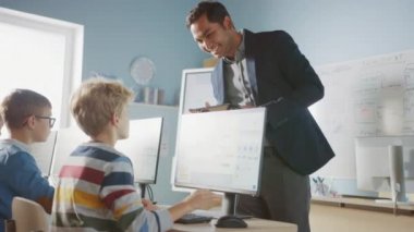 İlköğretim Okulu Bilgisayar Bilimi Sınıfı: Öğretmen Tablet Bilgisayar kullanıyor, Çeşitli Akıllı Çocuklar Grubuna Ders Açıklıyor, Bir Çocuğa Çak Beşlik Veriyor. Çocuklar için Bilişim Sınıfı