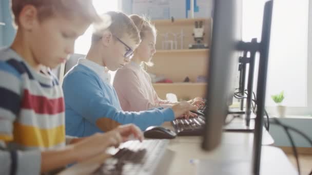 Sala de aula da escola primária: Retrato de um menino inteligente com óculos usa computador pessoal, aprendendo a usar a Internet com segurança, linguagem de programação para codificação de software. Educação Moderna para Crianças — Vídeo de Stock