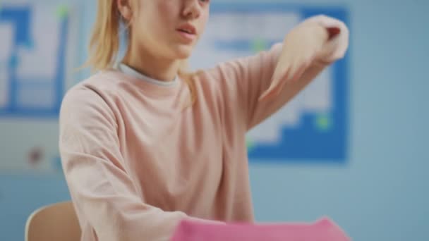 Elementary School Classroom : Portrait d'une jolie petite fille aux cheveux blonds et à la queue de cheval levant la main avec une réponse. Brillant jeune étudiant pose la question. Mouvement lent — Video