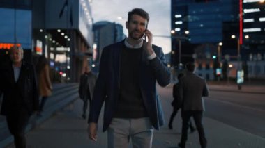 Takım Elbiseli Uzun İş Adamı Şehirde Yürürken Telefonda Konuşuyor. Keyifli bir konuşma yapıyor. Ofisteki insanlar geçiyor. 