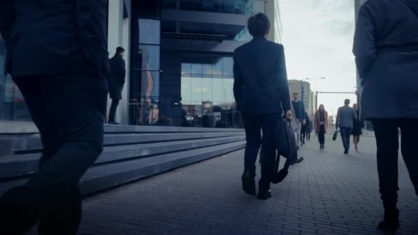 Irodavezetők és üzletemberek ingáznak munkába reggel vagy irodából egy felhős napon gyalog. A gyalogosok ügyesen öltözködnek. Sikeres emberek kezében Okostelefonok. — Stock videók