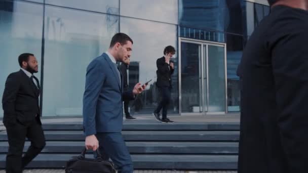 Büroleiter und Geschäftsleute pendeln morgens zur Arbeit oder an bewölkten Tagen zu Fuß aus dem Büro in die Innenstadt. Fußgänger sind lässig gekleidet. Erfolgreiche Menschen mit Smartphones. — Stockvideo