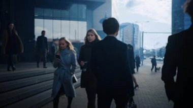 Sokakta yürüyen takım elbiseli bir iş adamı. Diğer ofis çalışanları işe ya da eve gidip geliyor. Sabahın erken saatleri ya da akşamın geç saatleri. Arkadan görüntüler. Şehir Işıkları Arkaplanda.