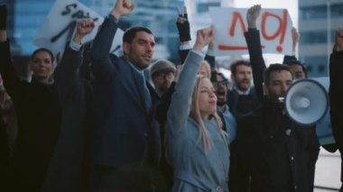 Çok Kültürlü Büro Yöneticileri ve İş Adamları bir caddenin dışında grev yapıyorlar. Kadın ve erkekler adalet için bağırıyor, ellerinde bir megafon, pankartlar ve posterler var. Ekonomik Kriz Grevi.