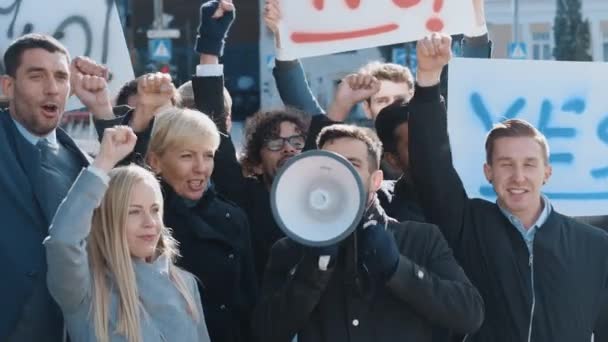 Wielokulturowi menedżerowie biur i biznesmeni pikietujący poza ulicą. Mężczyźni i kobiety krzyczą o sprawiedliwość, trzymają megafon, pikiety i plakaty. Strajk gospodarczy. — Wideo stockowe