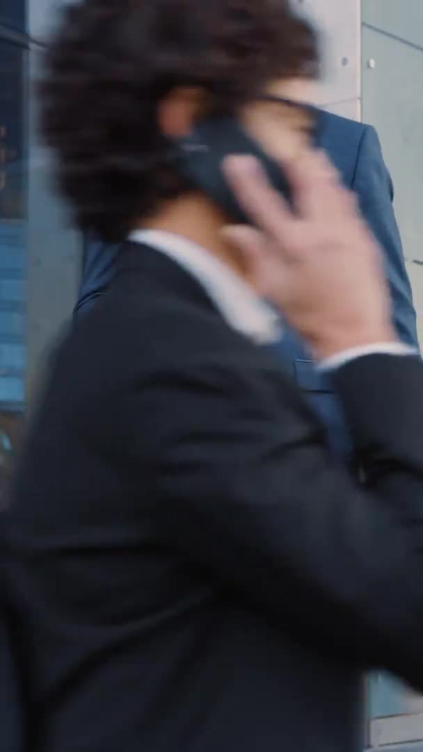 Suit 에 있는 캅카스 사업가가 다크 스트리트 에서 스마트 폰을 사용하고 있습니다. 다른 직원들은 과거를 걸어간다. 수직 스크린 오리엔테이션 9: 16 과 함께 한 비디오 동작. — 비디오