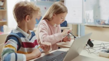Parlak Öğrenci Kız ve Öğrenci Konuşur ve Robot Mühendislik Sınıfı için Dizüstü Bilgisayar Kullanır. Teknoloji üzerine çalışan çocukların olduğu ilköğretim okulu bilim sınıfı. STEM Eğitimi