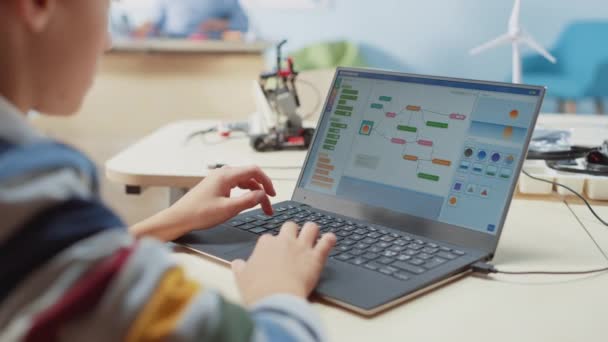 Smart Schoolboy использует ноутбук для программирования программного обеспечения для класса инженерии робототехники. Класс естественных наук начальной школы с одаренными гениальными детьми, работающими с технологиями — стоковое видео