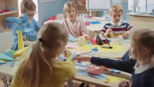 Bastelkurs der Grundschule: Vielfältige Gruppe schlauer Kinder hat Spaß bei einem Bastelprojekt, bei dem aus buntem Papier, Schere und Klebstoff lustige Papiermaché entsteht — Stockvideo
