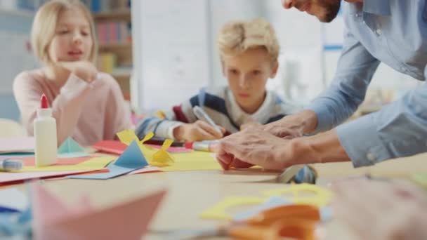 İlköğretim Okulu Sanatları ve El Sanatları Sınıfı: Coşkulu Öğretmen, Çeşitli Akıllı Çocuklar Grubu, Renkli Kağıt, Makas ve Yapıştırıcı kullanarak Eğlenceli Kağıt Mache Oluşturma Projesinde Birlikte Eğlendi — Stok video