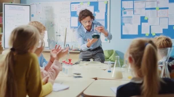 Elementary School Chemistry Classroom: Enthusiastic Teacher Teaches Group of Children, Shows Science Experiment by Mixing Chemicals in the Beaker (en inglés). Niños recibiendo educación moderna, aprendiendo cosas nuevas — Vídeos de Stock