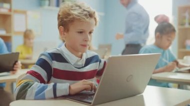 İlkokul Bilgisayar Bilimi Sınıfı: Akıllı Çocuk dizüstü bilgisayar kullanıyor, onun sınıf arkadaşları da dizüstü bilgisayarlarla çalışıyor. Çocuklar BTMM 'de Modern Eğitim Alırken, Oynarken ve Öğrenirken