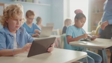 İlköğretim Okulu Bilgisayar Bilimi Sınıfı: Şirin Kız Dijital Tablet Bilgisayar kullanıyor, sınıf arkadaşları da dizüstü bilgisayarlarla çalışıyor. Çocuklar BTMM 'de Modern Eğitim Alırken, Oynarken ve Öğrenirken