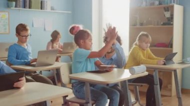 İlköğretim Okulu Bilgisayar Bilimi Sınıfı: Akıllı çocuk dizüstü bilgisayar kullanıyor, arkadaş canlısı öğretmen dersi anlatarak ona yardım ediyor, beşlik çakıyorlar. Çocuklar Modern Eğitime Gidiyor