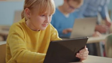 İlköğretim Okulu Bilgisayar Bilimi Sınıfı: Şirin Kız Dijital Tablet Bilgisayar kullanıyor, sınıf arkadaşları da dizüstü bilgisayarlarla çalışıyor. Çocuklar BTMM 'de Modern Eğitim Alırken, Oynarken ve Öğrenirken