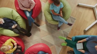 İlköğretim Okulu Yaratıcılık Sınıfı: Öğretmen onlara Dersi Açıklarken ve Dijital Tablet Bilgisayar Kullanırken Fasulye Torbaları Üzerinde Oturan Çocuklar, Çak Beşlik ile oynuyorlar. Üst Görünüm Kamerası