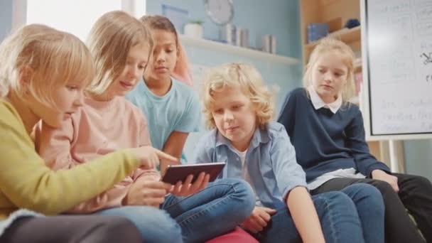 Diverse Group of Cute Small Children Sitting together on the Bean Bags Use Smartphone and Talk, Have Fun. Kids Browsing on Internet and Playing Online Video Games on Mobile Phone — Stock Video