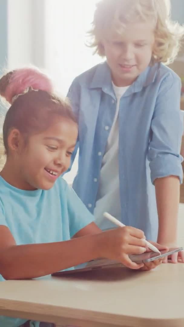 Porträt des süßen kleinen Mädchens und ihrer Klassenkameradin, die digitale Tablet-Computer benutzen, reden und Spaß haben. Videoaufnahmen mit vertikaler Bildschirmorientierung 9: 22 — Stockvideo