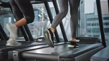 Koşu bandında koşan, spor yapan atletik insanlar. Modern Spor Salonunda Güçlü Kadınlar ve Erkekler Eğitimi. Spor İnsanlar Spor Kulübü 'nde çalışıyor. Bacaklara Odaklanarak Düşük Yerden Çekim