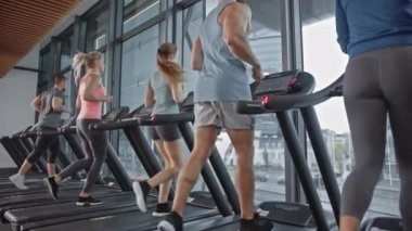 Koşu bandında koşan, spor yapan altı kişilik bir grup. Kaslı Kadınlar ve Erkekler Modern Spor Salonu 'nda Aktif Eğitimdeler. Spor İnsanlar Antrenmanı. Geri Görüntüleme Uzaklaştır ve Yavaş Hareket Kamerası