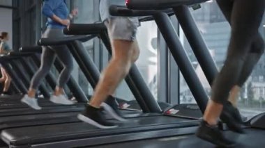 Koşu bandında koşan, spor yapan atletik insanlar. Modern Spor Salonu 'nda Atletik ve Kaslı Kadınlar ve Erkekler Aktif Eğitimdeler. Spor İnsanlar Antrenmanı. Arka Görünüm Yükselen Kamera