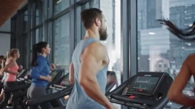 Kaslı Erkek Sporcu, Koşu bandında Koşarken Kablosuz Kulaklık, Podcast ya da Eğitim Çalma Listesi Kullanıyor. Güçlü Sporcular için Bacak ve Kardiyo Spor Günü. Arkaplanda Koşan Güzel Kadınlara Sığar