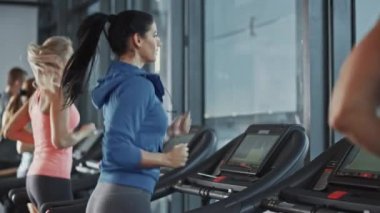 Koşu bandında koşan sağlıklı atletik kadın spor yapıyor. Kaslı Kadınlar ve Erkekler Modern Spor Salonu 'nda Aktif Eğitimdeler. Spor Salonu 'nda Spor İnsanları Antrenmanı. Yan Görünüm Yavaş Hareket