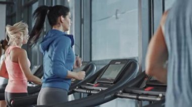 Kablosuz kulaklık takan Atletik Spor Kadını, spor salonunda koşu bandında koşarken Podcast veya Sport Music Playlist dinliyor. Formda Sporcular Eğitiminde. Yavaş Hareket Tarafı Görünümü