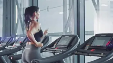Kablosuz kulaklık takan güzel sporcu kadın, koşu bandında koşarken Podcast veya Sport Music Playlist dinliyor. Sadece Spor Salonu 'nda Enerjik Kadın Atletizm Eğitimi. Yan Arka Görünüm