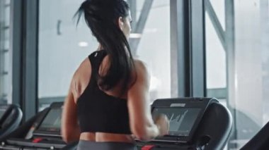 Kablosuz kulaklık takan güzel sporcu kadın koşu bandında koşarken Podcast veya Sport Music Playlist dinliyor. Sadece Spor Salonu 'nda Enerjik Kadın Atletizm Eğitimi. Yavaş Hareket Geri Görünümü