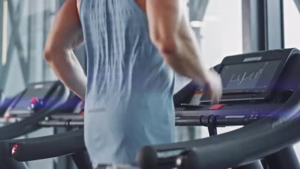 トレッドミル、脚、心臓の日に実行しているアスレチック筋肉マン。現代のジムフィットネスクラブでの強い男のトレーニング.Back View上半身を中心にスローモーションカメラショット — ストック動画