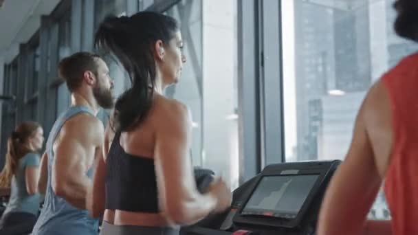 Beautiful Athletic Sports Woman Wearing Wireless Headphones, Listens to a Podcast or Sport Music Playlist while Running on a Treadmill. Fit Athletes Training in the Gym. Slow Motion Side View — Stock Video