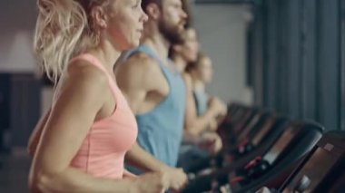 Koşu bandında koşan sağlıklı atletik kadın spor yapıyor. Kaslı Kadınlar ve Erkekler Modern Spor Salonu 'nda Aktif Eğitimdeler. Spor İnsanlar Spor Kulübü 'nde çalışıyor. Yan Görünüm Yavaş Hareket