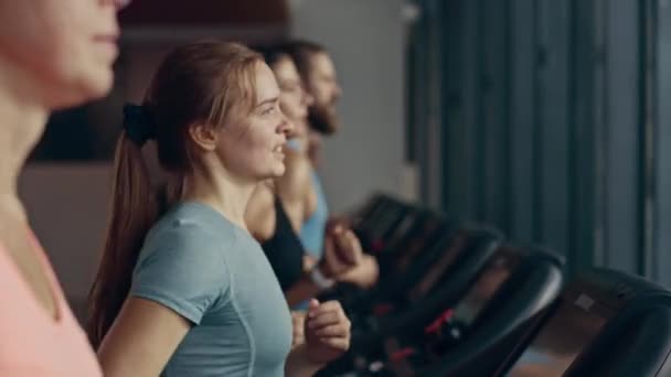 Bella donna sportiva atletica che corre su un tapis roulant. Atleta donna in forma energetica che si allena in palestra. Allenamento degli atleti nel Fitness Club. Ritratto con vista laterale al rallentatore — Video Stock