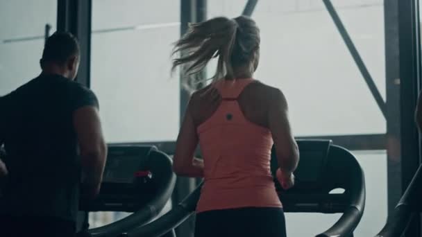 Atletische mensen lopen op loopbanden, doen fitness-oefening. Atletische en gespierde vrouwen en mannen Actieve training in de moderne fitnessruimte. Sport Mensen Workout. Achteraanzicht Bewegende Slow Motion Camera — Stockvideo