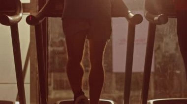 Koşu bandında Koşan Atletik Kaslı Adam, Bacak ve Kardiyo Günü. Pencere Kenti Manzaralı Modern Spor Salonu 'nda Güçlü Adam Eğitimi. Geri Görüntülü Yavaş Hareket Kamerası Görüntüsü. Altın Saat Gündüz