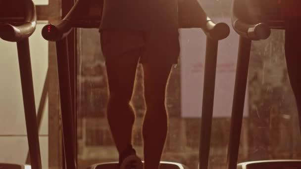 Athletic Muscular Man Running on a Treadmill, Leg and Cardio Day (en inglés). Entrenamiento de hombre fuerte en el gimnasio moderno Club de fitness con vista al paisaje urbano de la ventana. Vista trasera Cámara de cámara lenta. Hora dorada durante el día — Vídeos de Stock
