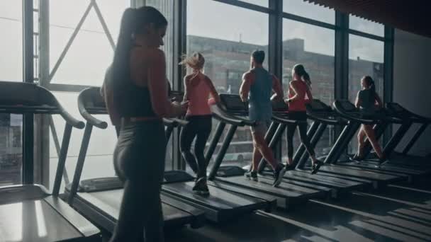 漂亮的女运动员在健身俱乐部的健身房里用智能手机散步。使用社交媒体，张贴图片，交流，检查电子邮件。背景下的跑步机跑步运动员 — 图库视频影像
