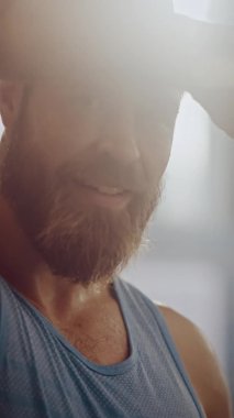 Sakallı erkek sporcunun portresi. Alnından terli kolsuz gömlek mendili ve kaslı eliyle. Sıkı egzersizden sonra yakışıklı adam, antrenman. Dikey Ekran Yönlendirme Videosu 9: 16