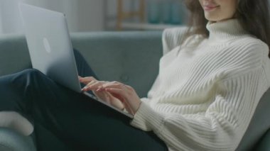 Güzel Genç Kadın, dizüstü bilgisayarda çalışırken sandalyede oturuyor. Süveter giyen Şehvetli Kız Not Defteri 'nde çalışır, çalışır, internette sörf yapar, rahat bir dairede dinlenirken sosyal medyayı kullanır