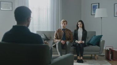Psikoterapistle danışmanlık seansında olan genç bir çift. Terapistin Not Almasına Bakış: Analizci Kanepede oturan Genç İnsanlar, Psikolojik Travma ve İlişki Sorunlarını Tartışıyor