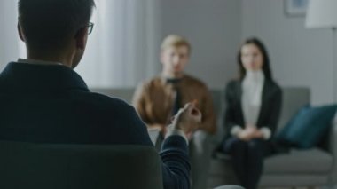 Psikoterapistle Danışmanlık seansına odaklanmamış çift. Not Tutan ve Konuşan Terapistin Arkasına Odaklan: Analizci Koltuğa Oturan, Psikolojik ve İlişki Sorunlarını Tartışan İnsanlar