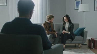 Psikoterapistle danışmanlık seansında olan genç bir çift. Terapistin Not Almasına Geri Bakış: Koltukta oturan, Elleri Dokunan, İlişki Sorunlarını Tartışan, Çözüm Bulma
